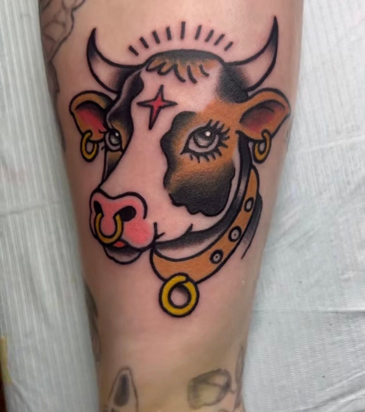 Traditional colour tattoo of a cow's head wearing a nose ring, on a lower leg.