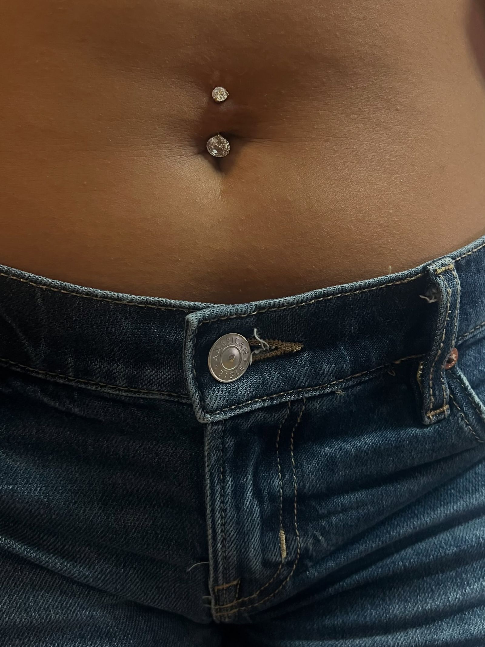 A healed navel piercing with a jewelled barbell.
